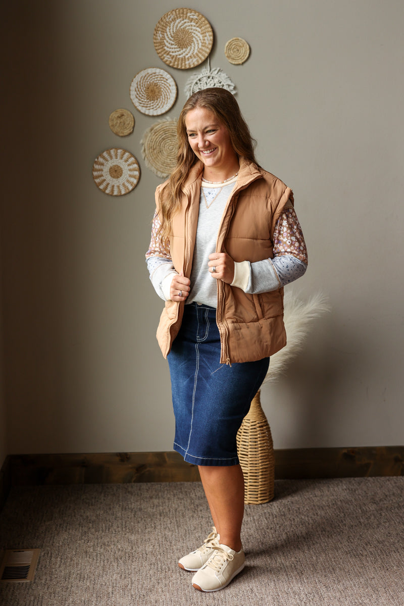beige tan puffer vest oversized layered over a colorblock fall top with a denim skirt and sneakers