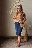 Full outfit view of a camel mock neck sweater with a dark denim midi skirt, tall brown boots, and a tan bag.