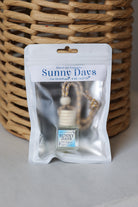 A Honey Jar Creations 'Sunny Days' car oil diffuser in its original white resealable pouch packaging, set against a woven wicker basket background.