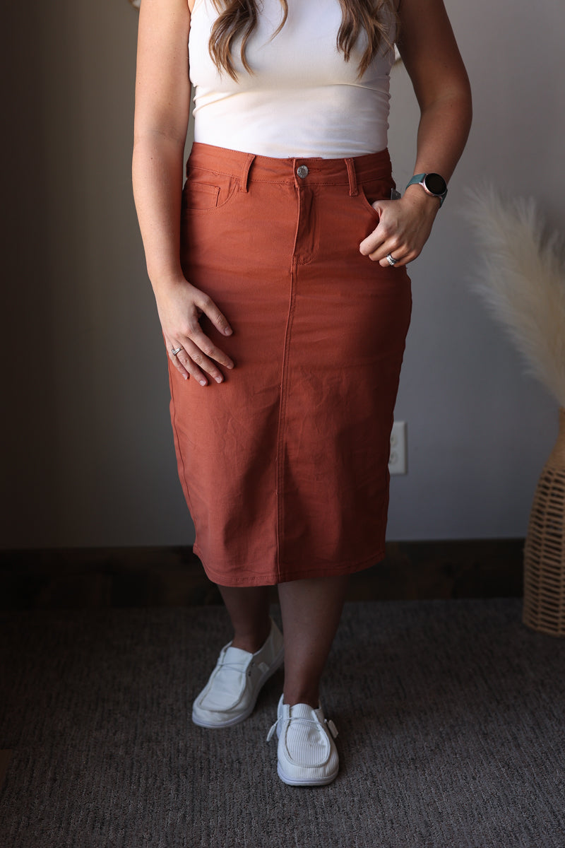 Person wearing a rust-colored skirt and white sneakers indoors.
