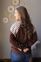 Back view of a coffee brown sweatshirt with plaid shoulder panels and solid brown sleeves.