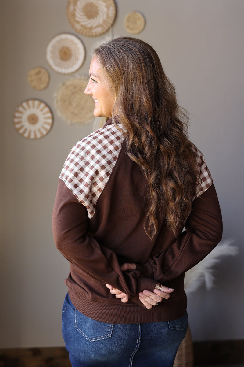 Back view of a coffee brown sweatshirt with plaid shoulder panels and solid brown sleeves.