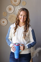 Front view of a light grey and blue colorblock hoodie styled with a dark denim skirt.