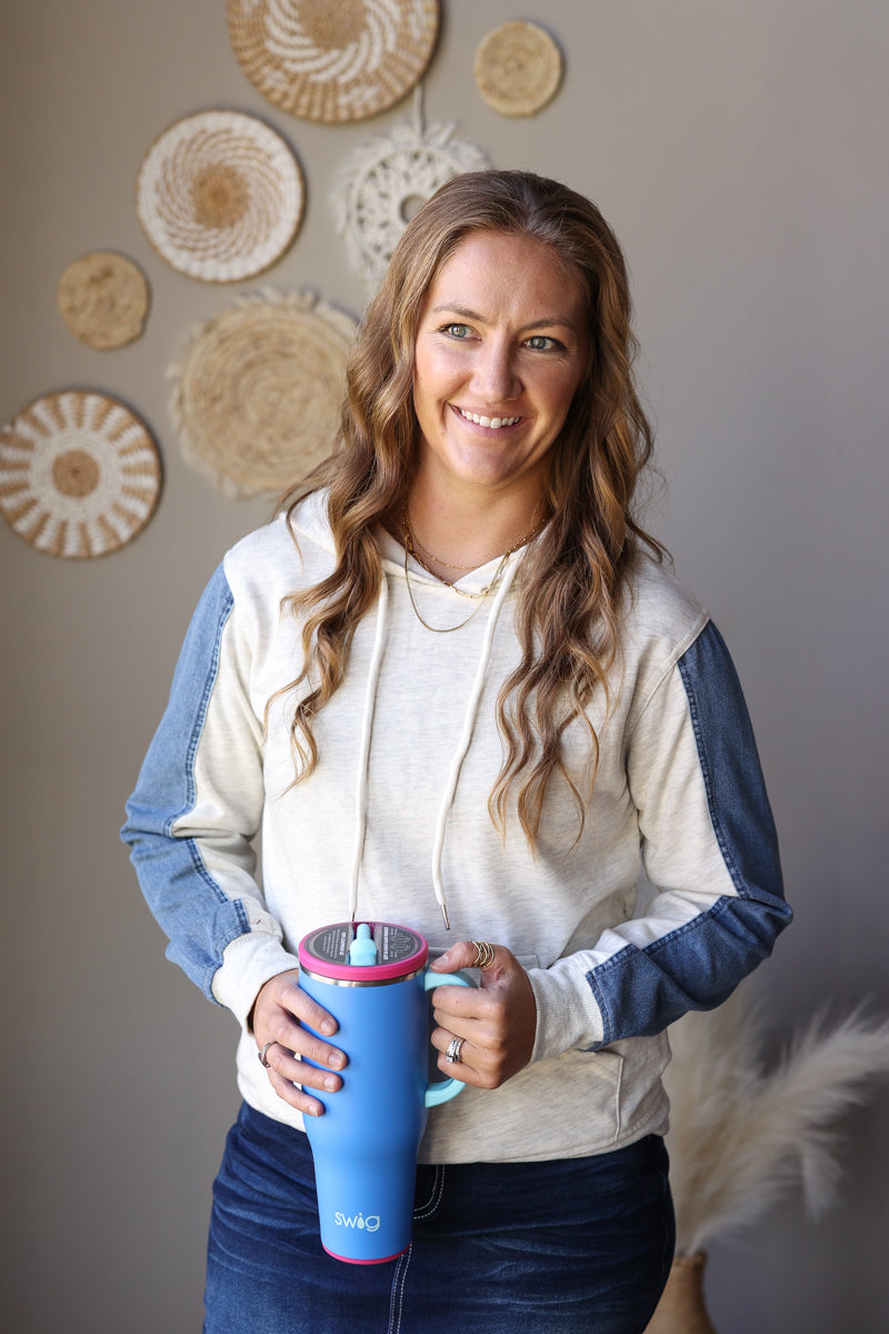Front view of a light grey and blue colorblock hoodie styled with a dark denim skirt.