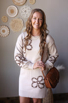 Parchment floral knit dress showing brown flower motifs, long puff sleeves, and a ribbed hem.