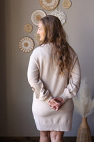 Back view of a parchment long sleeve sweater dress showing the plain knit back and ribbed hem.