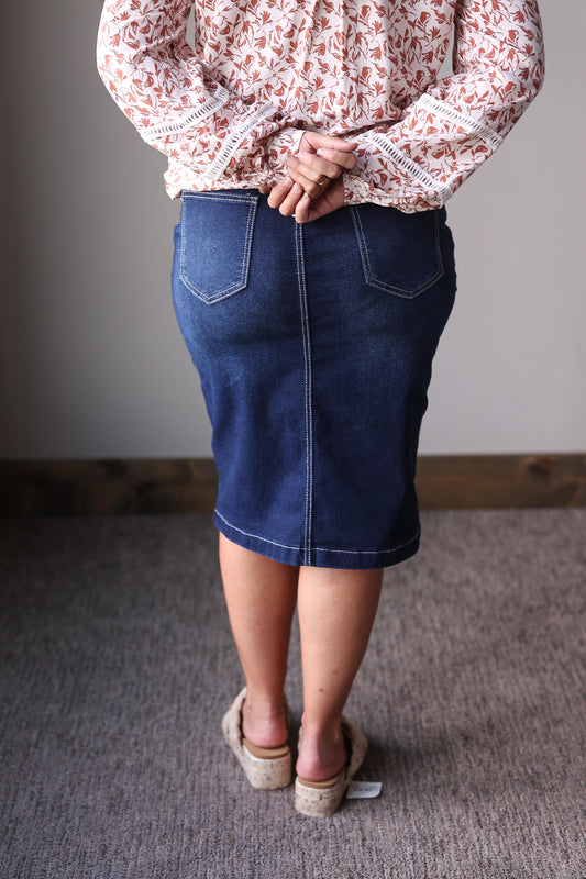 Person wearing a floral blouse and blue denim skirt standing at Classy Closet online womens modest boutique