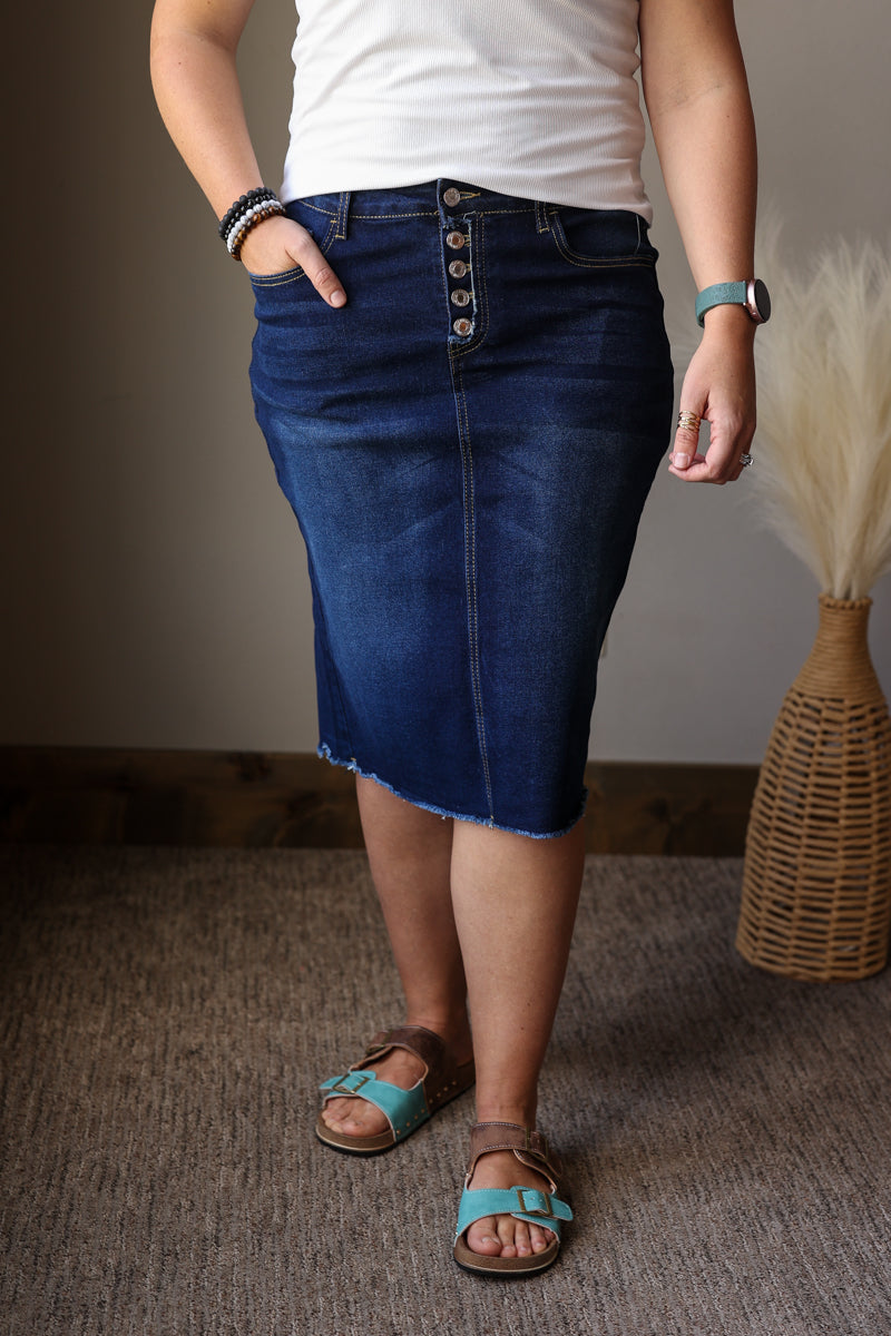 Person wearing a blue denim skirt with a plain background
