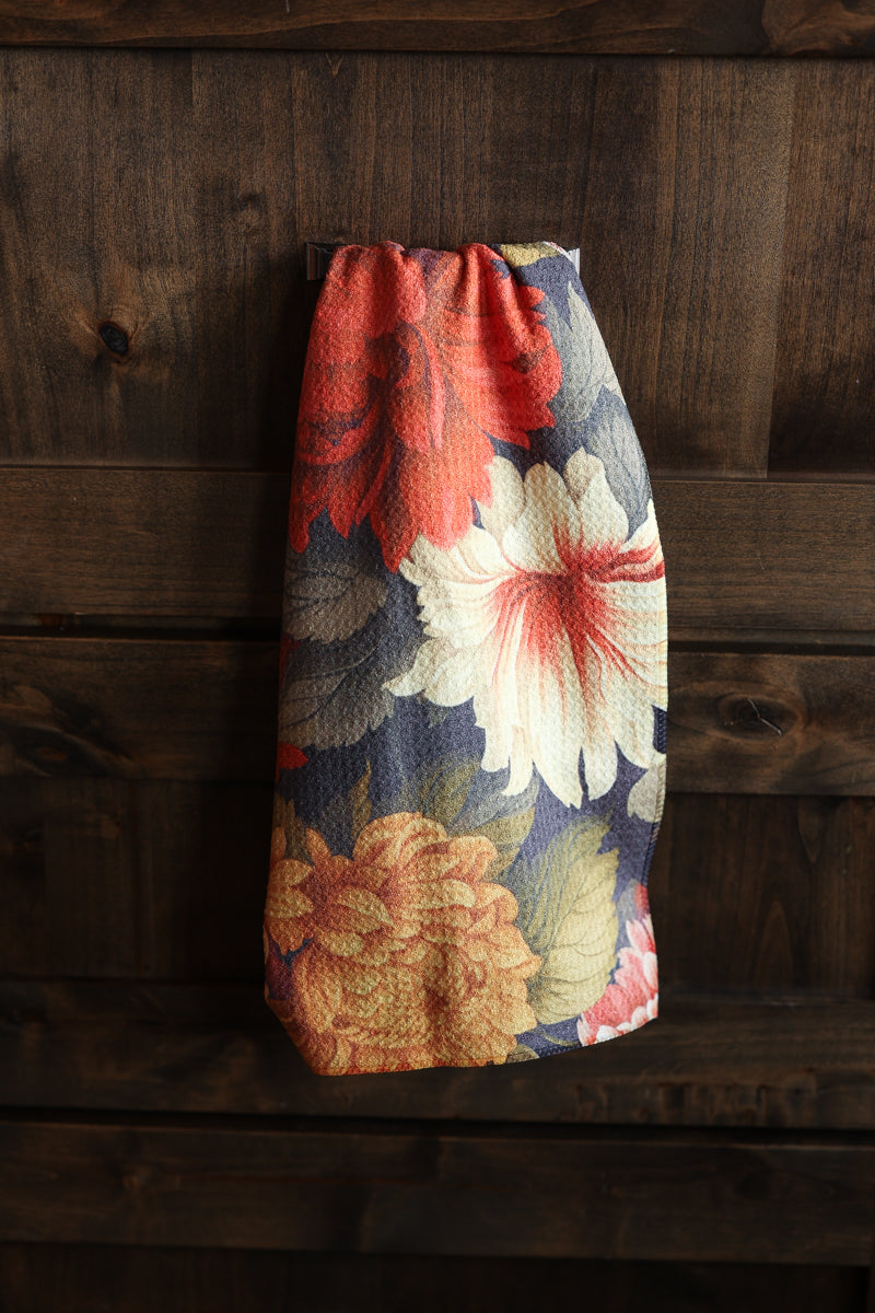 A fabric drawstring pouch with a vintage floral print, hanging against a dark rustic wooden plank background.