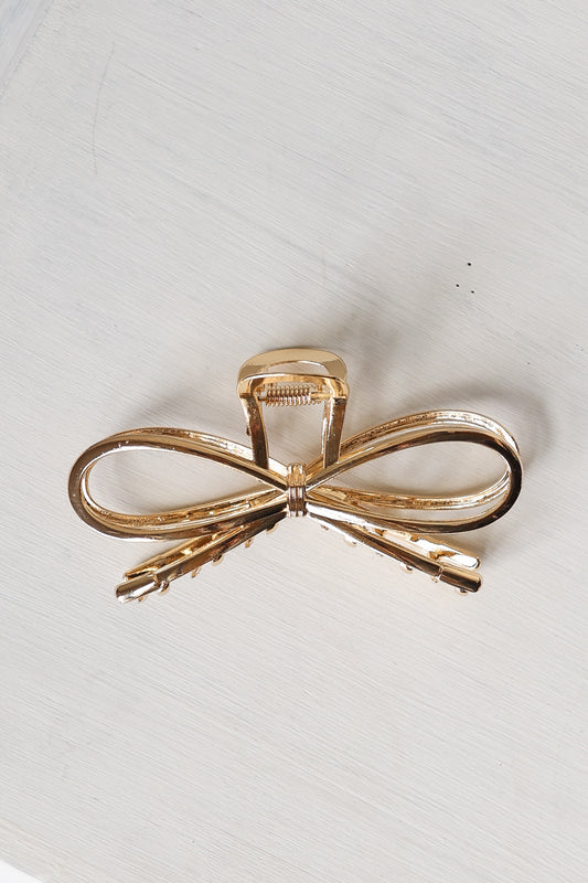 Gold bow-shaped hair clip on a light gray background