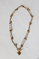Gold necklace with heart-shaped pendant on a white background
