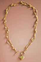 Gold necklace with a heart pendant on a beige background