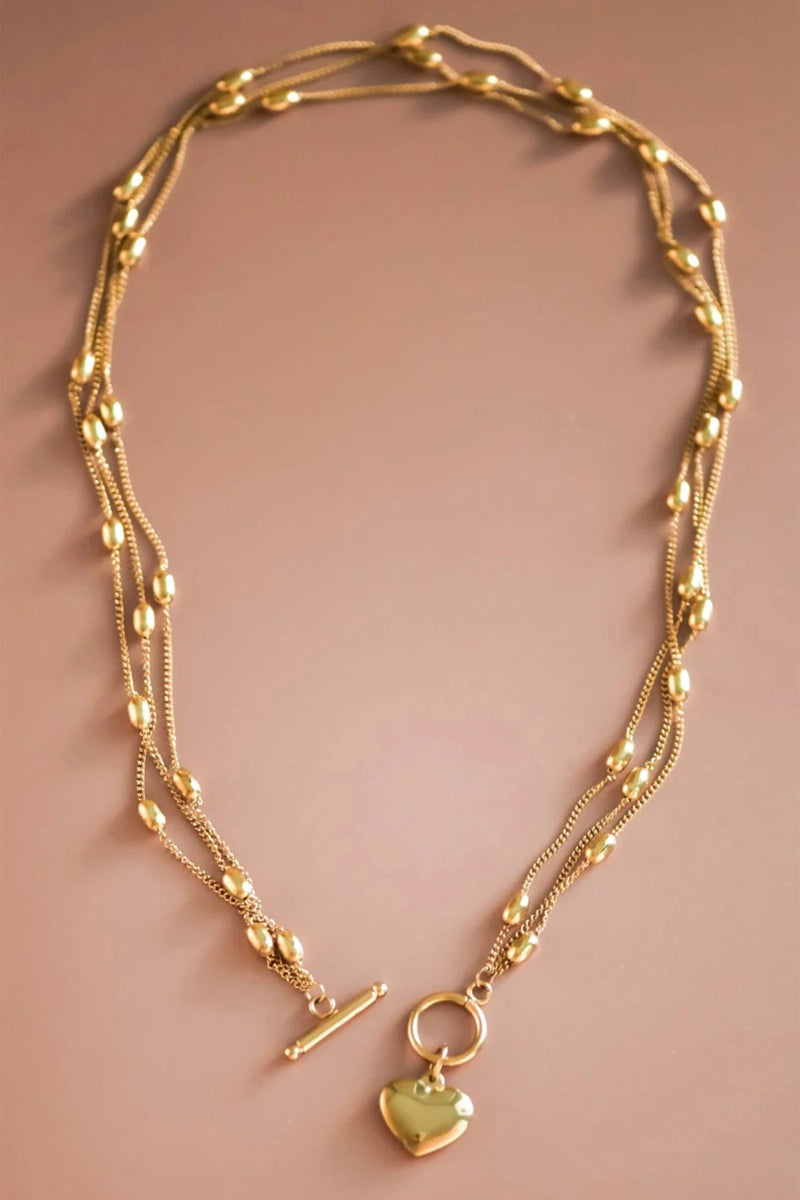 Gold necklace with a heart pendant on a beige background