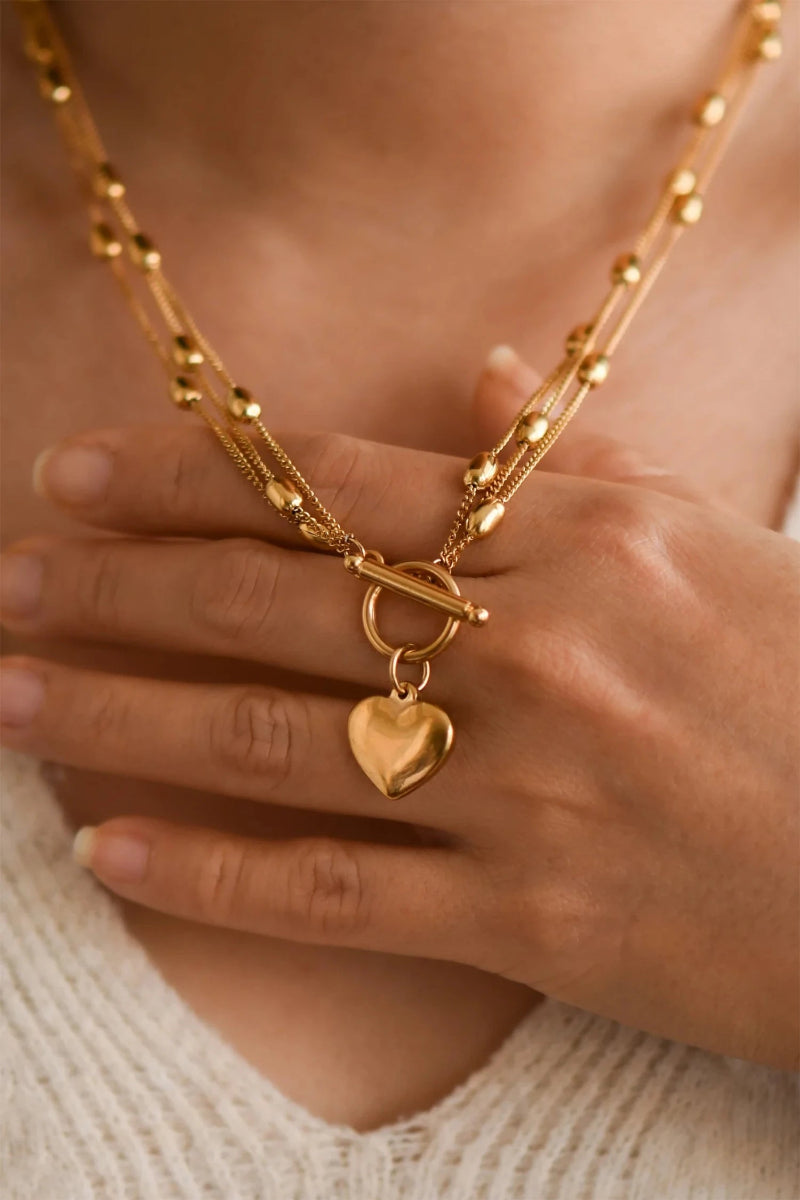 Gold necklace with a heart pendant worn by a person