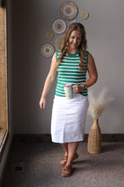 Woman in a green and white striped shirt and white skirt standing in a room with decorative wall plates.