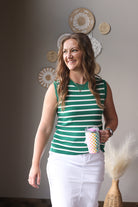 Woman wearing a green and white striped shirt holding a colorful mug indoors.
