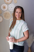 Woman holding a white mug with decorative wall art in the background