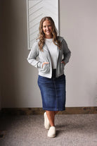 Woman wearing a gray jacket, white shirt, blue skirt, and white shoes for casual fall/winter outfits 2025. 