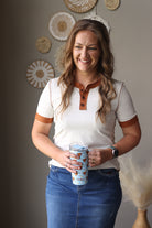 Woman holding a tumbler with decorative wall in the background