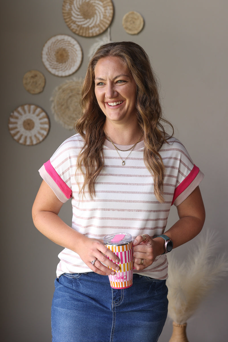 Woman holding a striped mug with decorative wall art in the background