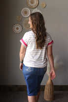 Woman wearing a striped shirt and blue skirt standing in a room with decorative wall art.