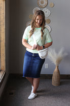 Woman in a striped shirt and blue skirt standing in a room with decorative elements.