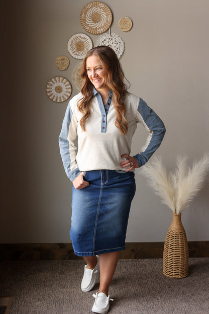 woman standing wearing a light grey and denim henley blouse and midi denim skirt for spring outfits