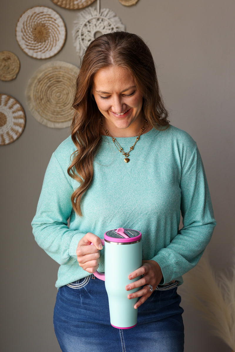 ash teal soft long sleeve crew top on a woman standing along a neutral wall