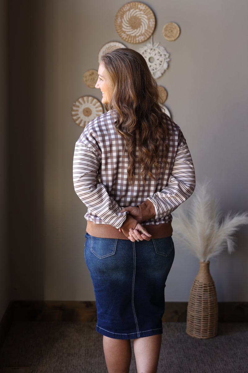 Back view of a brown and cream gingham top styled with a dark denim skirt.