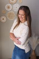Woman wearing a striped shirt and jean skirt standing in front of decorative wall art.