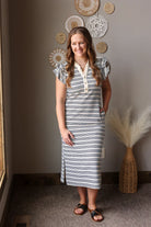 Woman wearing a striped dress standing in a room with decorative wall hangings.