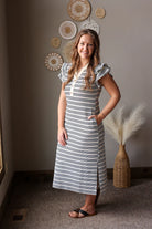 Woman in a striped dress standing in a room with decorative plates on the wall.