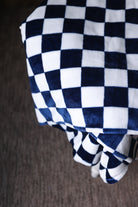 Folded checkered blanket with blue and white pattern on a brown surface