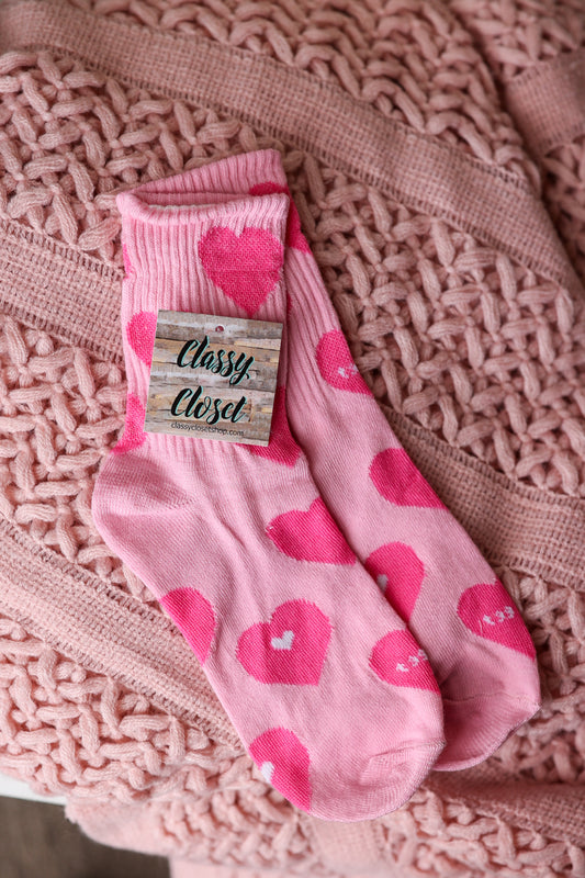 Pink socks with heart patterns on a textured pink fabric background