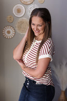 Woman wearing a striped shirt standing against a wall with decorative plates.