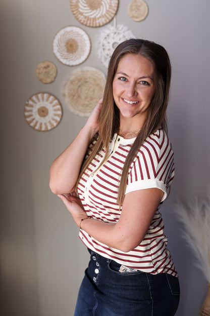 Woman wearing a red and white striped shirt with decorative plates on the wall behind her.