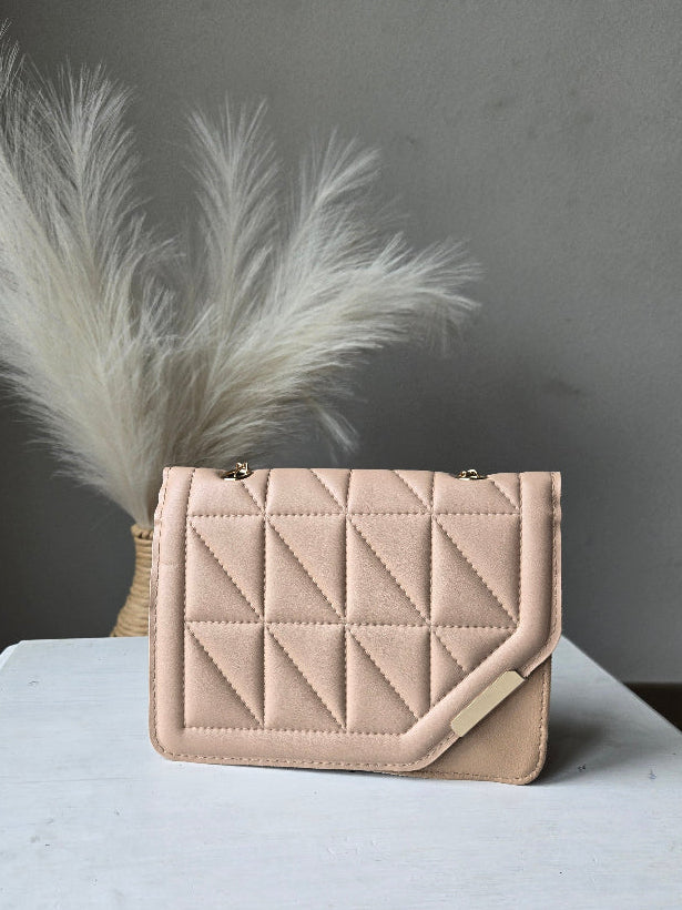 A light beige quilted leather clutch bag with a geometric diamond pattern, displayed on a white surface next to a white decorative feather.