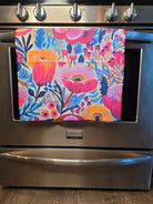 A stainless steel KitchenAid range oven with a colorful floral patterned towel hanging on the handle.