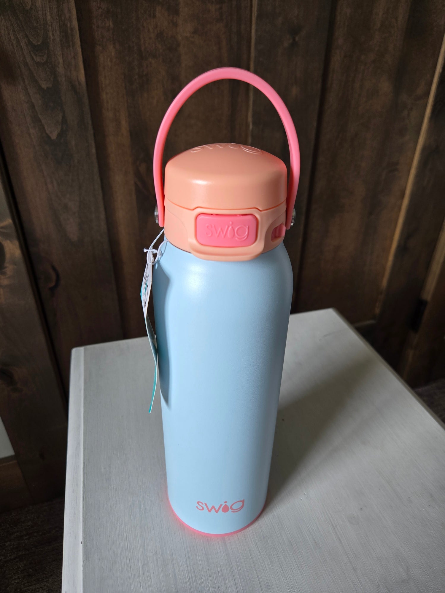 Light blue thermos with pink handle on a wooden surface