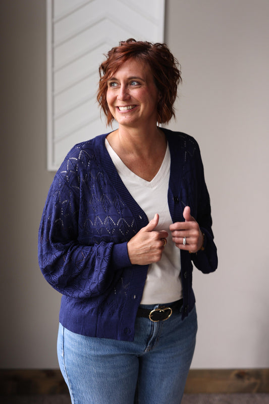 Woman wearing a blue cardigan over a white shirt, standing for fall winter outfits
