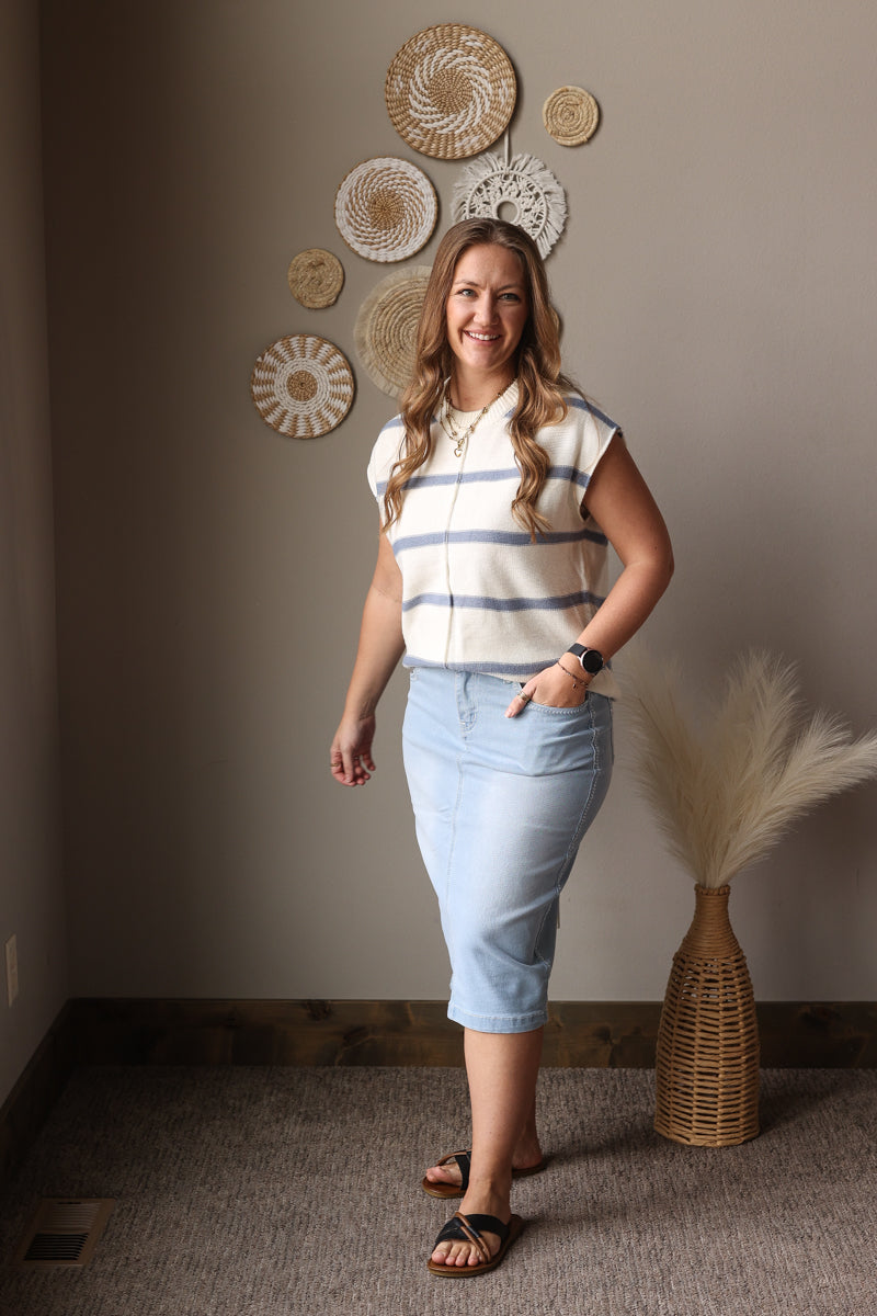Woman standing in a room with decorative wall art and a vase.