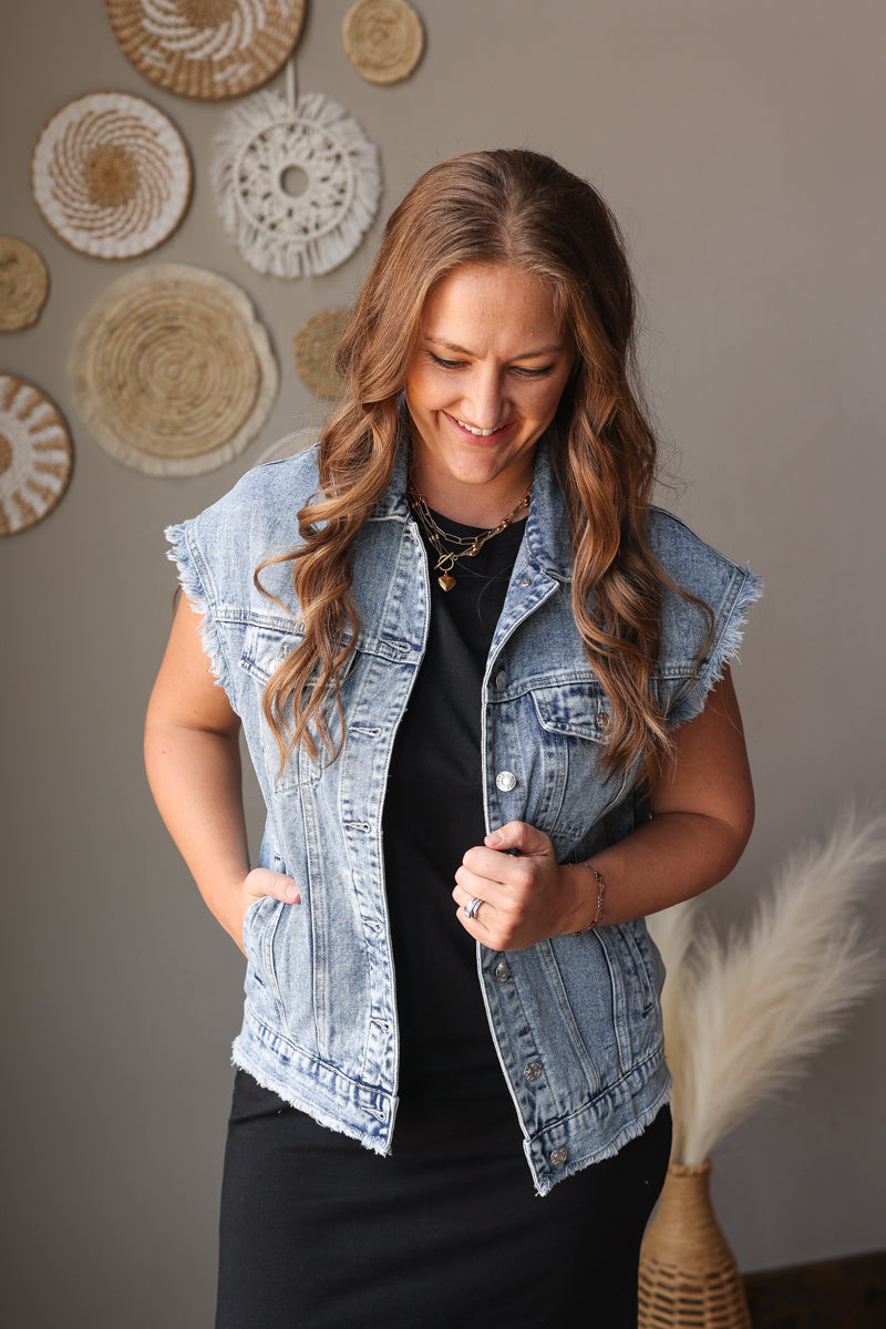 Woman wearing a denim vest in front of decorative wall art