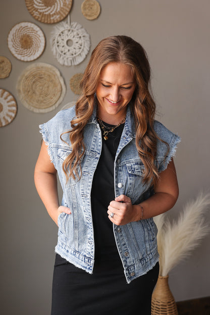 Woman wearing a denim vest in front of decorative wall art