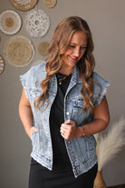Woman wearing a denim vest indoors with decorative wall art in the background