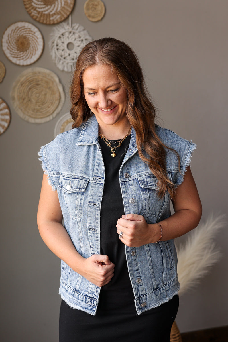 Woman wearing a denim vest against a wall with decorative plates.