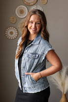 Woman wearing a denim vest standing against a wall with decorative elements.