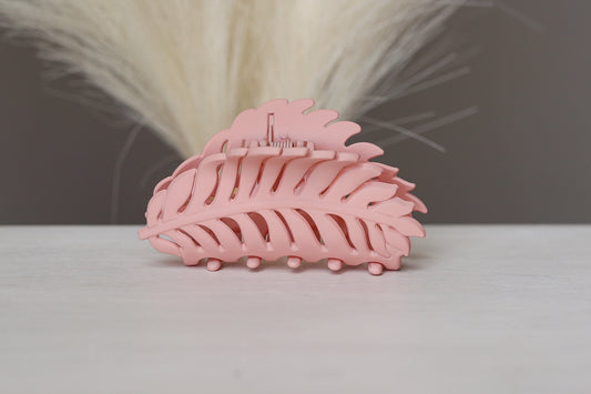 Pink hair clip on a white surface with a blurred background
