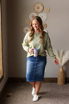 spring green and mocha colorblock splice sweatshirt on a woman standing for spring outfits with a midi denim skirt
