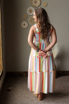 Woman wearing a colorful striped dress standing in a room with decorative wall art.