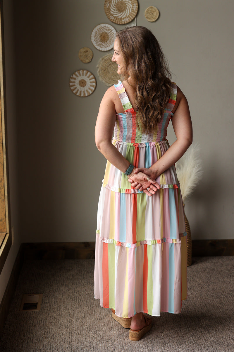 Woman wearing a colorful striped dress standing in a room with decorative wall art.